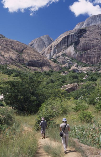 MADAGASCAR, Ambalavao, A tourist being lead by a guide towards rocky mountains and trees in the