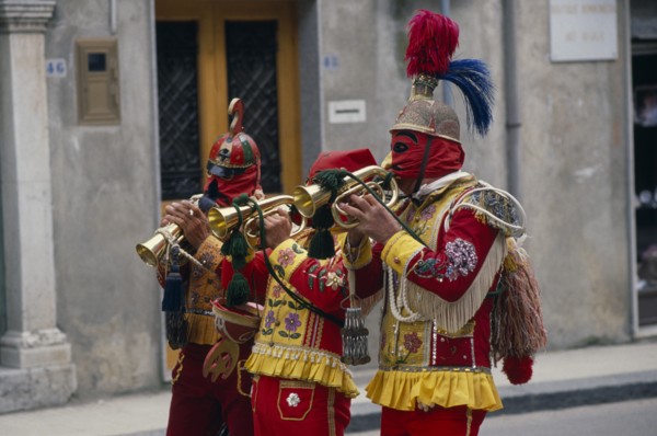 ITALY, Sicily, San Fratello, Bugle players wearing red and yellow costumes and masks celebrating