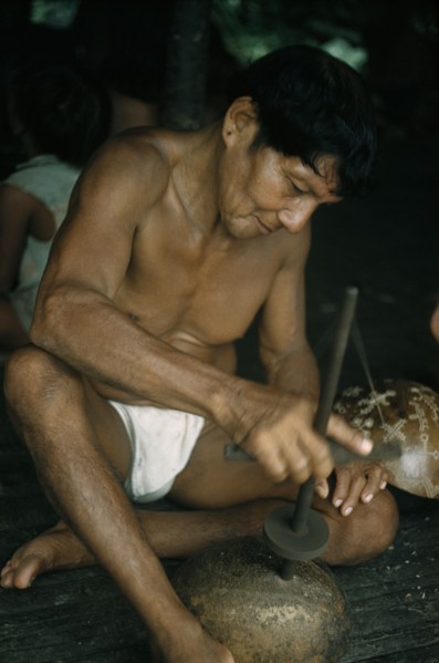 COLOMBIA, Choco Region, Noanama Tribe, Man drills holes in a gourd to make a colander for straining
