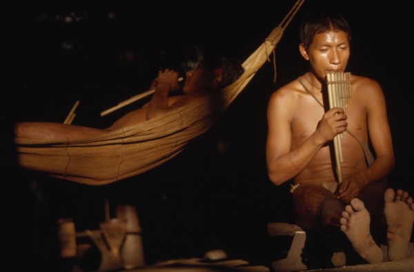 COLOMBIA, Vaupes Region, Tukano Tribe, "Boys playing panpipes at dusk in entrance to maloca /