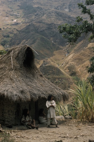COLOMBIA, Sierra Nevada de Santa Marta, Kogi Tribe, "Young man stands outside the family home above
