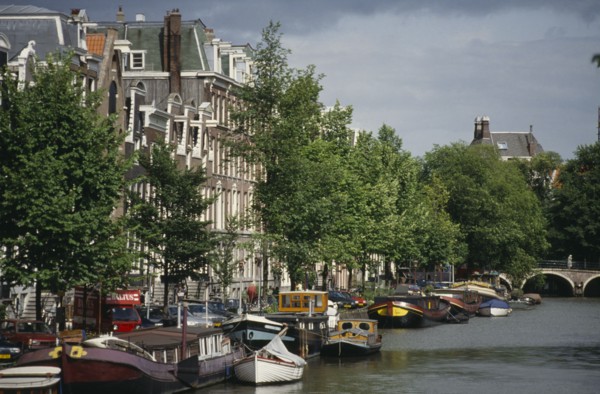 HOLLAND, Amsterdam, Canal and moored houseboats and barges overlooked by traditional architecture.