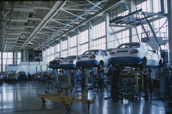 UKRAINE, Zaporozhye, Cars raised off the ground with staff working underneath in a production