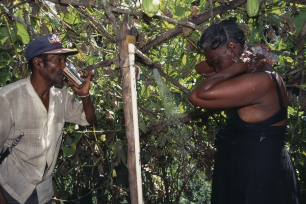 DOMINICAN REPUBLIC, Water, Man drinking water and a woman washing under a shower from a aqueduct
