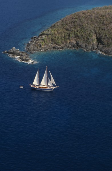 WEST INDIES, US Virgin Islands, St Thomas, Elevated view over sailing boat passing rocky projectory