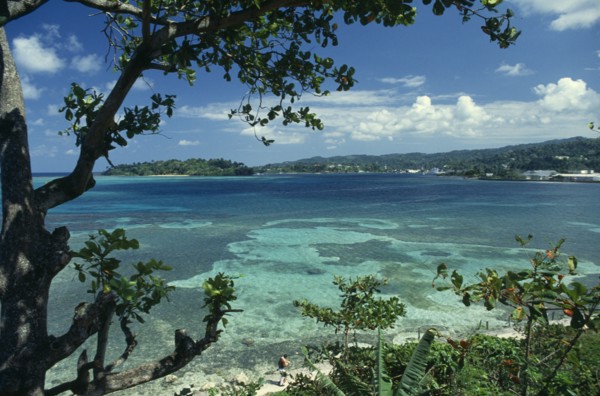 WEST INDIES, Jamaica, Port Antonio, View across turquoise sea towards beach and tree covered coast