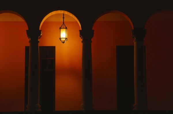 PUERTO RICO, San Juan, Exterior of building at night with pillars and arches and a single light
