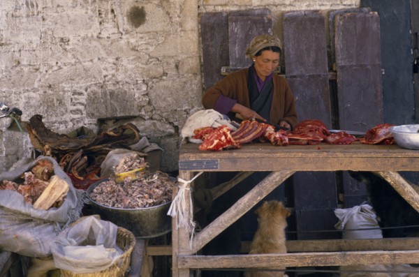 TIBET, Lhasa, Female vendor with yak meat for sale in Jokhang market.
