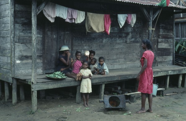MADAGASCAR, Mananara, Local family sitting on raised wooden veranda of their home with line of