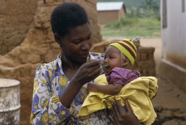 TANZANIA, People, Mother feeding baby daughter with a spoon.