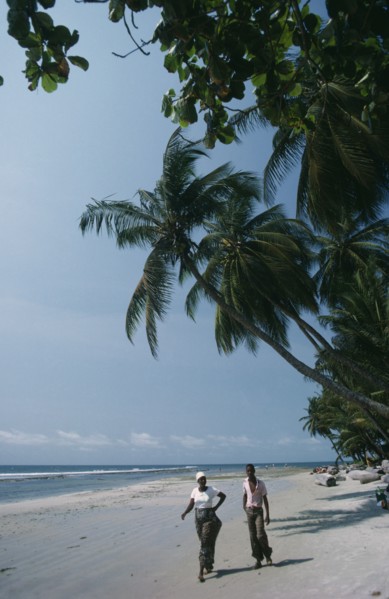 GABON, Landscape, Cape esteries. Man and woman walking along sandy beach lined with overhanging