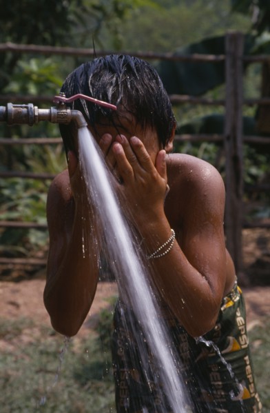 LAOS, Water, Child in Hmong village washing with water from UNHCR supplied tap.