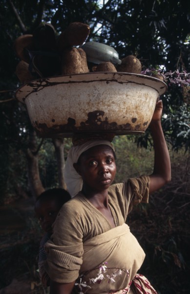GHANA, People, Women, Portrait of young woman carrying bowl of yams on her head and baby in sling