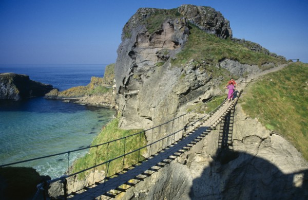 IRELAND, County Antrim, Carrickarede, Visitors crossing narrow rope bridge on the Irish coast.