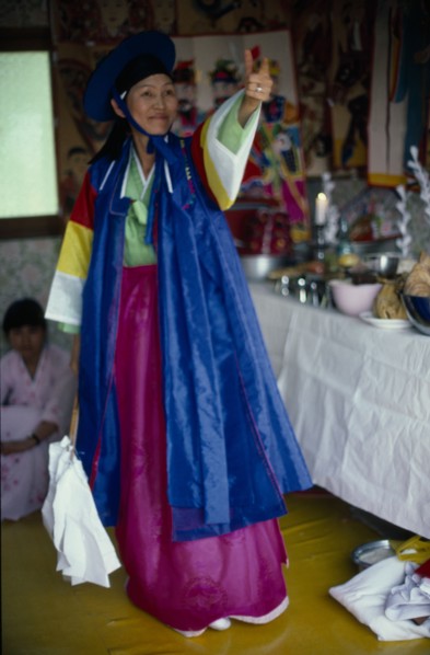 SOUTH KOREA, Religion, Shamanism, Female Shaman with arm raised in air at a funeral wearing