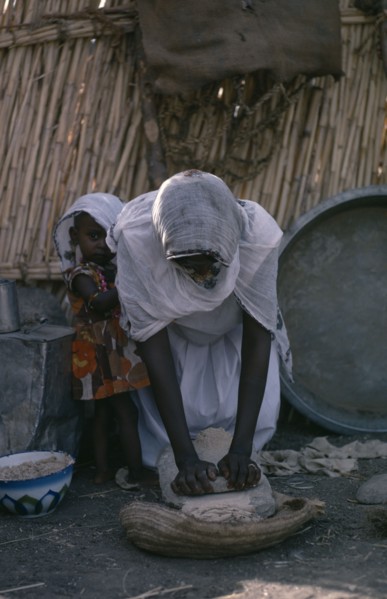 SUDAN, Food and Drink, Woman making bread with young child beside her.
