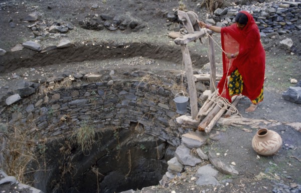 INDIA, Rajasthan, Banswada, Woman collecting water from open well.