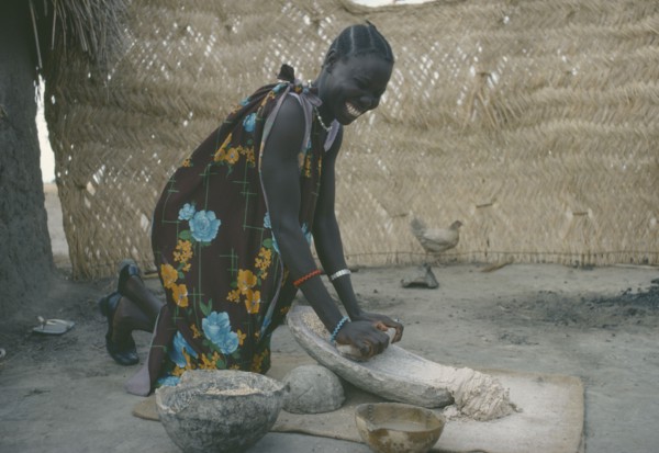 SUDAN, People, Shilluk woman grinding sorghum to make bread.