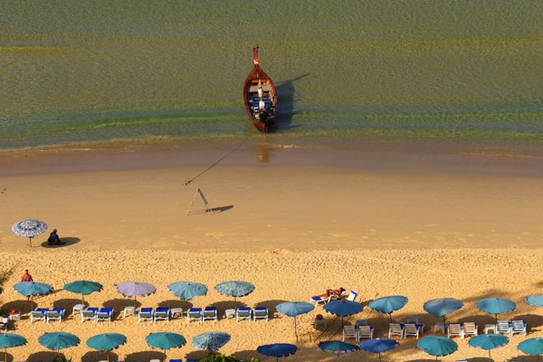 THAILAND, Phuket, Karen Beach, Sun umbrellars on golden sandy beach with boat at shoreline.