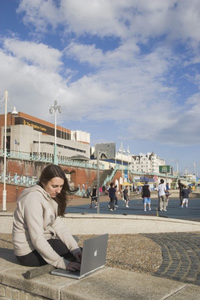 ENGLAND, East Sussex, Brighton, Woman using a laptop to surf the internet  in the free WiFi zone on