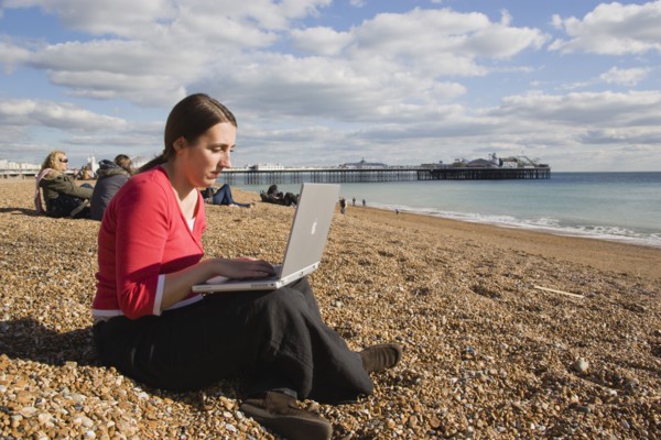 ENGLAND, East Sussex, Brighton, Woman using a laptop to surf the internet  in the free WiFi zone on