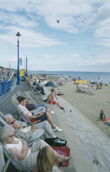 ENGLAND, Dorset, Bournemouth, People sat on deckchairs along seafront.