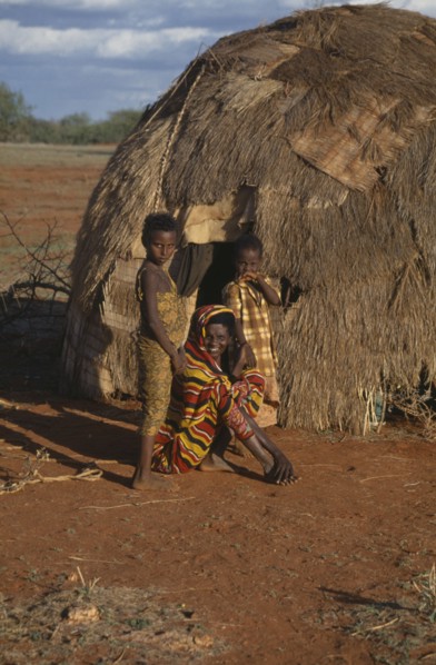 SOMALIA, Gedo, Woman and her two daughters outside their hut.