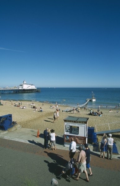 ENGLAND, East Sussex, Eastbourne, View from promenade across busy beachfront and pier.