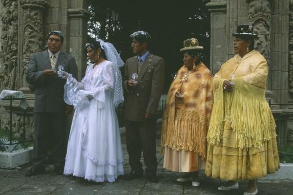 BOLIVIA, La Paz, Wedding in El Monticulo. Bride and guests standing under archway.