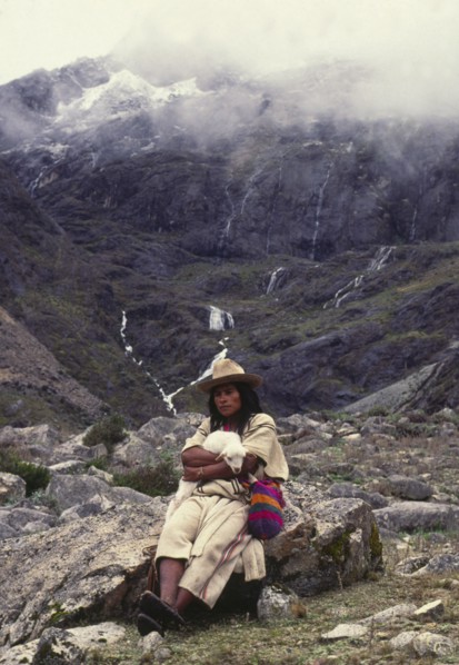 COLOMBIA, Santa Marta, Sierra Nevada , "Ica Indian with lamb sat on a rock, surrounded by mountains