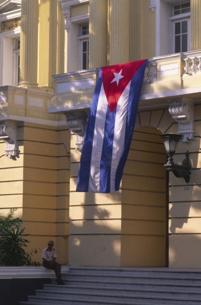 CUBA, Santiago de Cuba, "Security guard sat outside government building, flying Cuban flag."