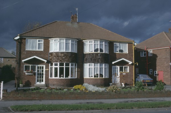 ENGLAND, Yorkshire, Leeds, Semi detached housing with a single car parked in the driveway.