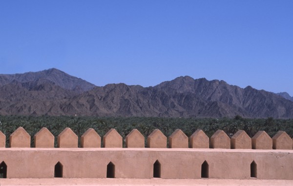 OMAN, Landscape, "Wall of a traditional fort, with Oasis and mountains behind."