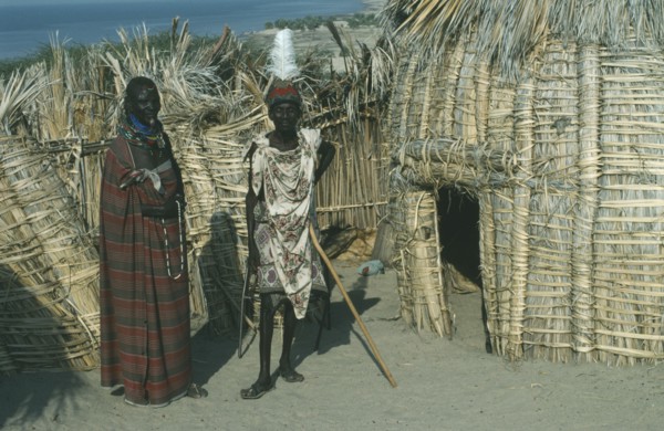KENYA, Lake Turkana, "Turkana tribe, two men standing outside a traditional hut made from dry fan
