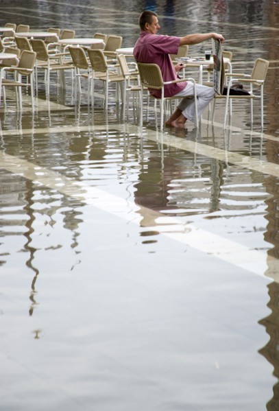 ITALY, Veneto, Venice, Aqua Alta High Water flooding in St Marks Square with an artist painting a