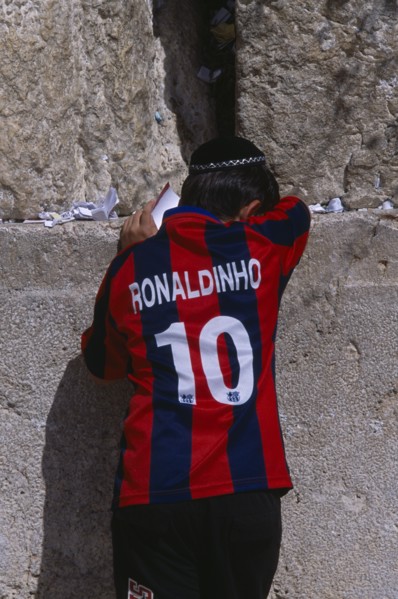 ISRAEL, Jerusalem, An Israeli boy wearing a Ronaldinho football shirt praying at the Western Wall.