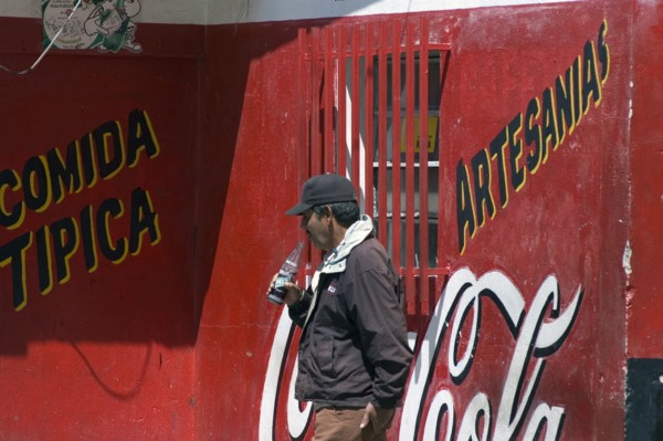 VENEZUELA, Merida state, Apartaderos, "Man drinking a soft drink next to a Coca Cola advert,