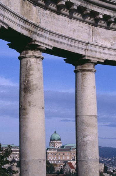 HUNGARY, Budapest, Copper dome of the Royal Palace rooftop and cityscape seen between stone pillars