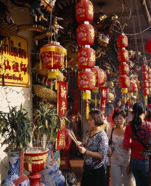 THAILAND, Bangkok, China Town, Wat Traimit.  People offering prayers and incense at temple
