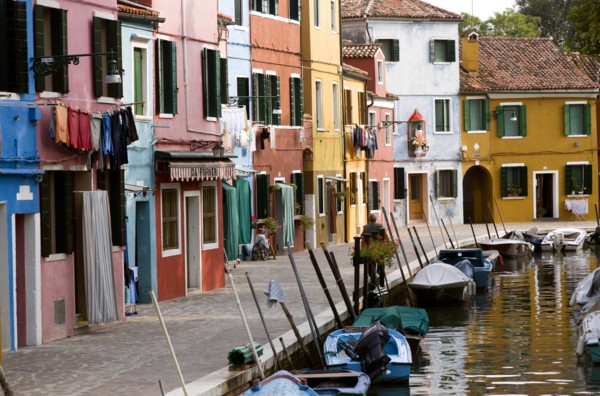 ITALY, Veneto, Venice, Colourful houses beside a canal on the lagoon island of Burano with boats