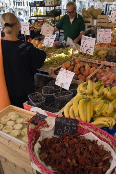 ITALY, Veneto, Venice, Fruit and vegetable stall in the Rialto market with shopper and vendor