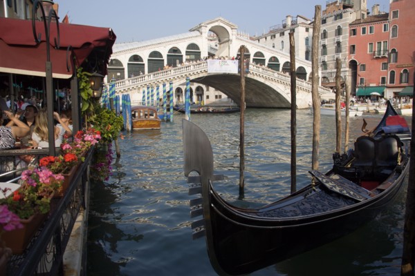 ITALY, Veneto, Venice, A gondola moored beside a restaurant on the Grand Canal with tourists dining