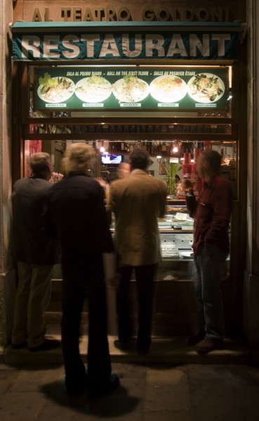 ITALY, Veneto, Venice, Men standing and eating at the street window of a restaurant near the