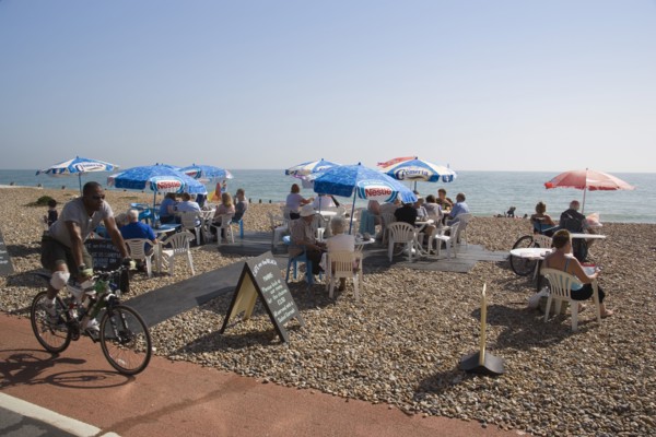 ENGLAND, West Sussex, Worthing, Beach front Cafe with people sitting at tables under parasols on