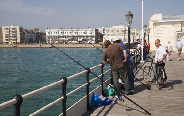 ENGLAND, West Sussex, Worthing, Men fishing off the pier
