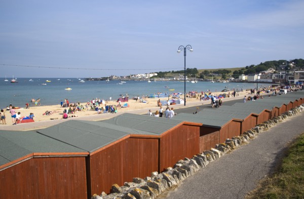 ENGLAND, Dorset, Swanage Bay, View across beach hut roofs towards sandy stretch of beach and sea