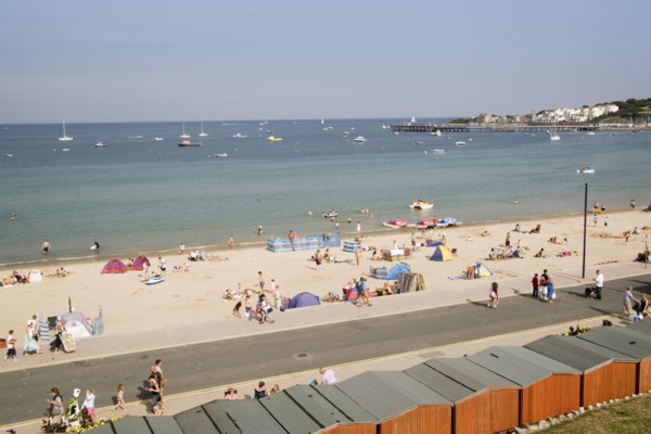 ENGLAND, Dorset, Swanage Bay, Elevated view over beach huts towards busy stretch of sandy beach and