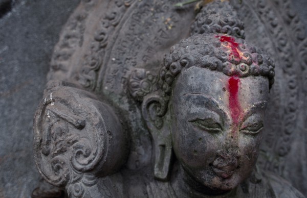 NEPAL, Kathmandu, Detail of Buddha statue anointed with pink powder.