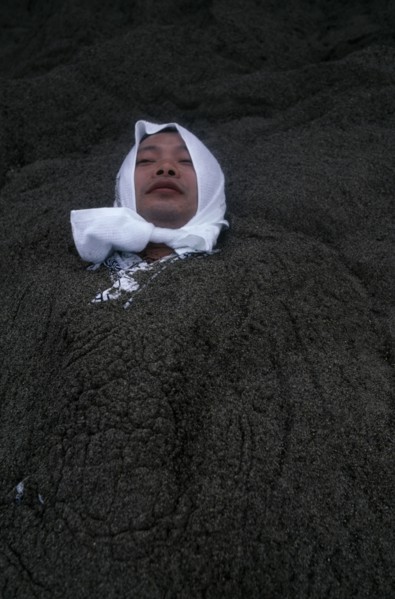 JAPAN, Kyushu, Ibusuki, Sunabulo. Hot Sand Bath with a man wearing a white towel wrapped around his