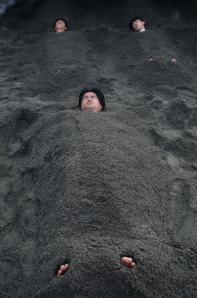 JAPAN, Kyushu, Ibusuki, Sunabulo. Hot Sand Bath with men submerged in sand with only heads and feet